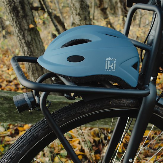 Lichtblauwe fietshelm met ventilatieopeningen, op een fietsendrager.