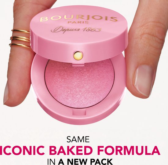 Hand met gouden ringen houdt een roze Bourjois Little Round Pot blush met spiegel en gebakken poeder vast.