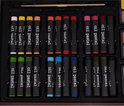 Close-up van 24 oliepastels, georganiseerd per kleur in een kunstenaars koffer.