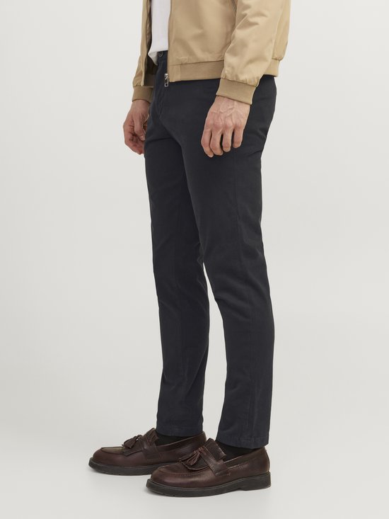 Man, zijaanzicht, met beige bomberjack en zwarte chino.