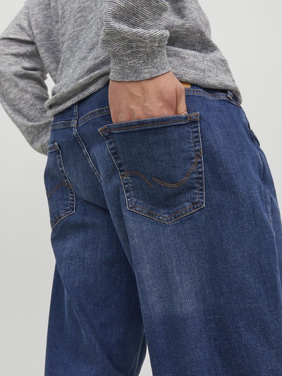 Detail van de achterzakken van een spijkerbroek van blauw denim met oranje stiksels.