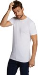 Een man in een wit T-shirt met ronde hals en een spijkerbroek, krabt aan zijn hoofd.