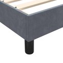 Close-up van de hoek van een donkergrijs fluwelen boxspringframe met een zwarte poot.