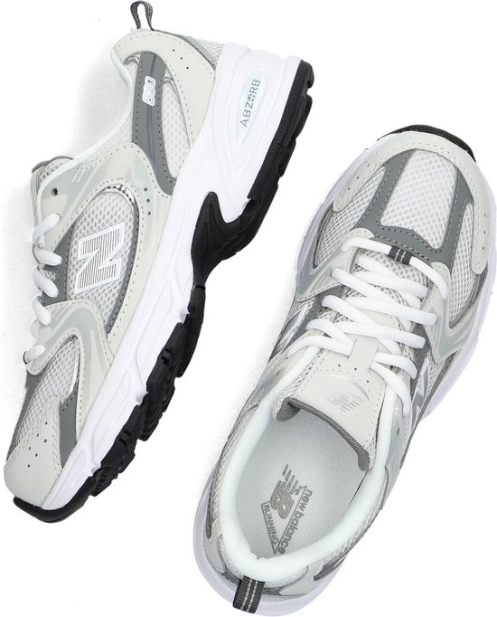 Een paar lichtgrijze New Balance sneakers met witte veters en ABZORB demping.
