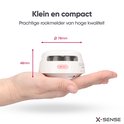Kleine, compacte witte rookmelder met een diameter van 78 mm en hoogte van 48 mm, rustend in een handpalm.