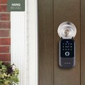 Zwarte Varin smart sleutelkluis hangt aan een donkerbruine deur naast een sleutelgat.