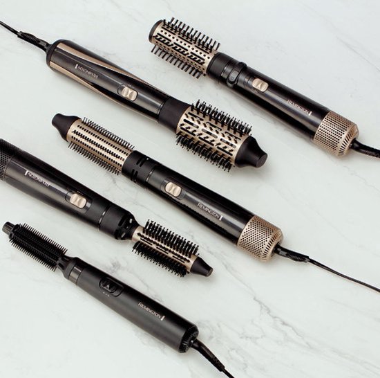 Vijf zwarte Remington föhnborstels met gouden accenten en verschillende opzetborstels, liggend op een marmeren ondergrond.