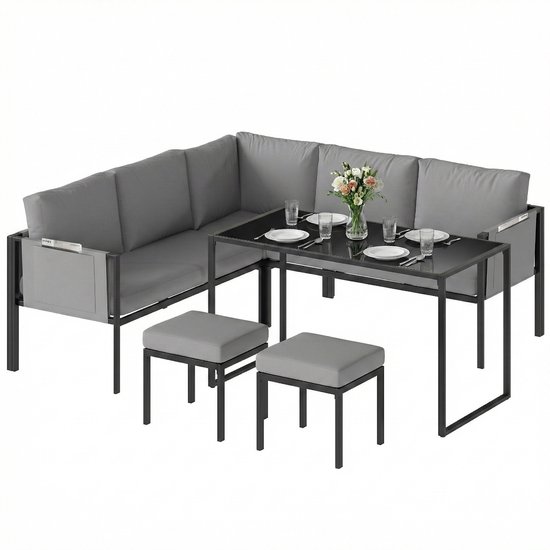Grijze hoekbank, glazen tafel en twee poefs op een witte achtergrond.