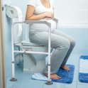 Zwangere vrouw in pyjama zit op een toilet met een witte toiletbeugel.
