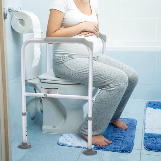 Zwangere vrouw in pyjama zit op een toilet met een witte toiletbeugel.