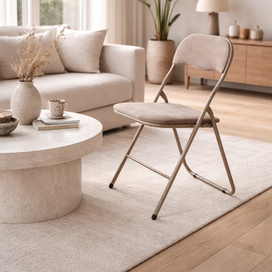 Une chaise pliante en velours taupe dans un salon, avec un dossier incurvé, sur un tapis crème.