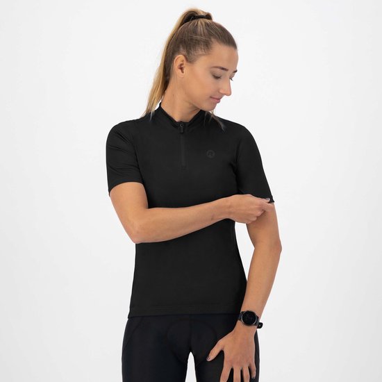 Vrouw met paardenstaart draagt een zwart fietsshirt met korte mouwen, half-zip hals en een logo op de borst.