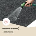 Tapis gris foncé nettoyé à l'eau avec un tuyau d'arrosage, montrant le nettoyage.