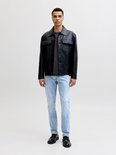 Model in zwart leren jack, grijs t-shirt en lichtblauwe slim fit jeans.