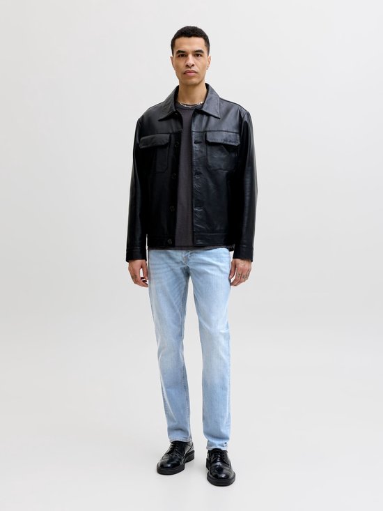 Model in zwart leren jack, grijs t-shirt en lichtblauwe slim fit jeans.
