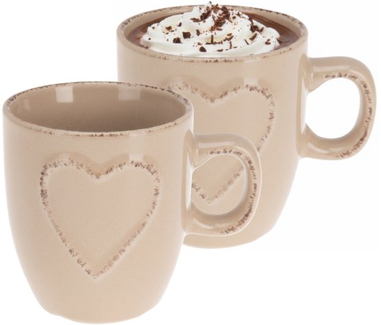 Twee crèmekleurige mokken met verhoogd hartmotief, één gevuld met chocolademelk en slagroom.