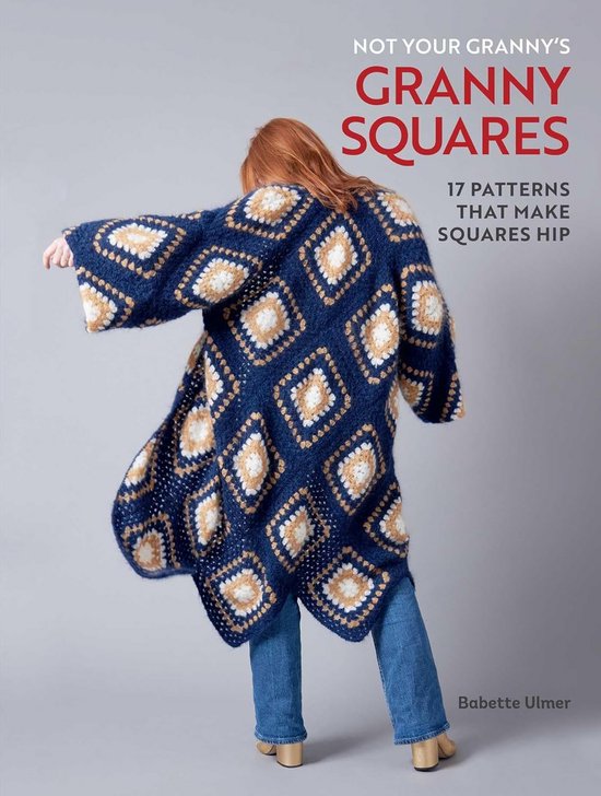 Mannequin portant une longue veste bleue tricotée avec des motifs à carreaux beiges et blancs, sur un jean.