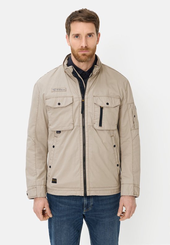 Man in beige Camel Active blouson met opstaande kraag, twee borstzakken, rits en jeans.