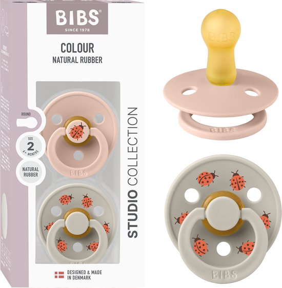 Verpakking van BIBS spenen. Eén roze speen met lieveheersbeestje, één zandkleurige speen met lieveheersbeestjes. Maat 2, natuurrubber. Studio Collection.