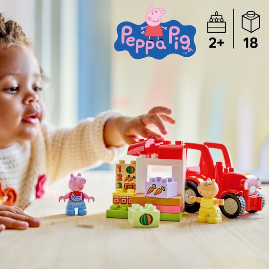 Kind speelt met LEGO Duplo Peppa Pig tractor, marktkraam, Peppa en George.