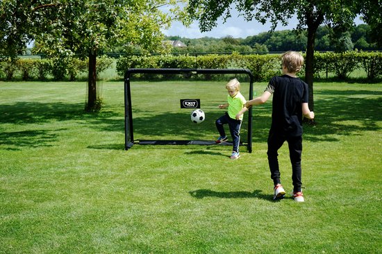 Jongens spelen voetbal op een grasveld met een zwart EXIT voetbaldoel.