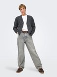Een man draagt een grijze jeans met rechte pijpen, een wit shirt, een grijze vest en bruine instappers.