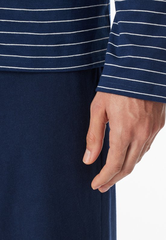 Close-up van de arm van een man in een donkerblauw pyjamashirt met fijne witte strepen.