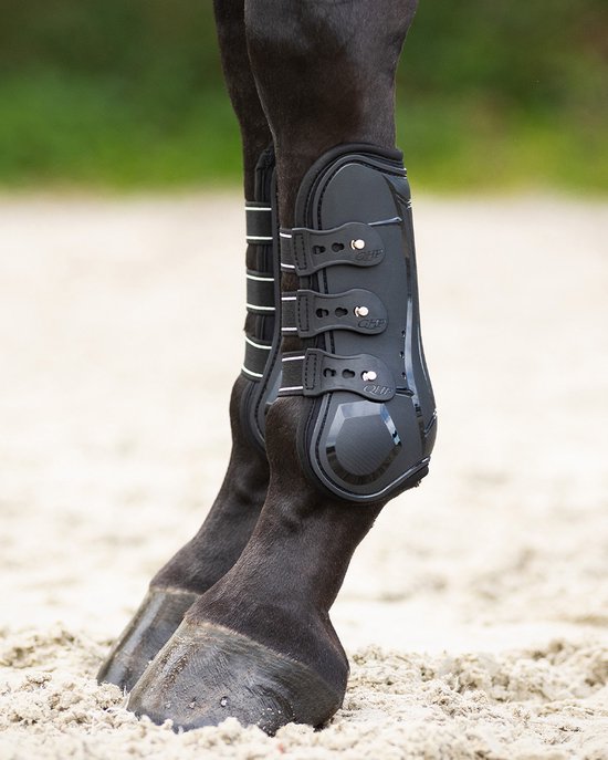 Zwarte peesbeschermers met witte bandjes, gedragen op de voorpoten van een paard.
