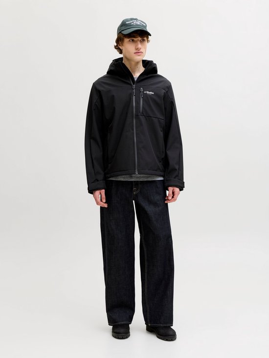 Man met zwarte softshell jas met capuchon, open rits en 'JJ Studio. Jack & Jones' logo, staand op witte achtergrond.
