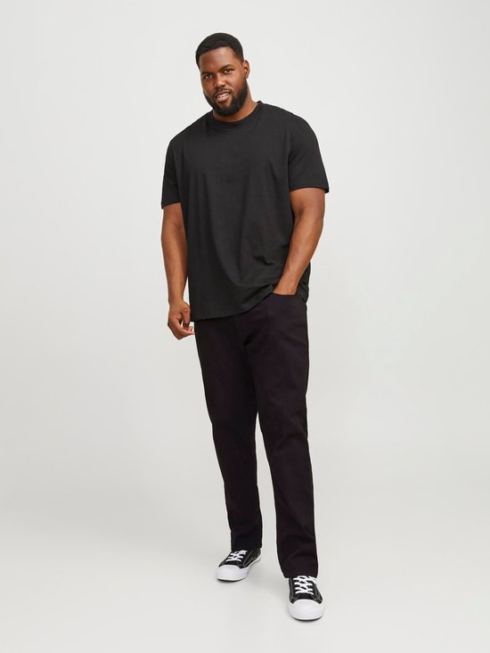 Man draagt een zwarte T-shirt en zwarte jeans met witte sneakers met zwarte veters.