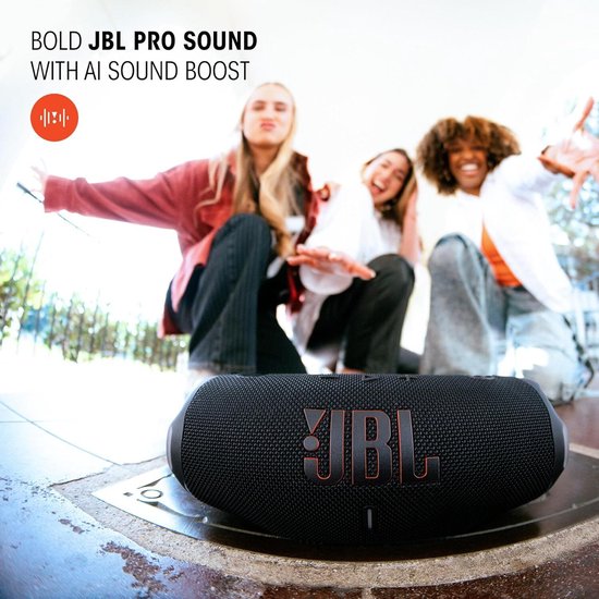 Zwarte JBL Charge 6 speaker op de grond met drie lachende vrouwen op de achtergrond.