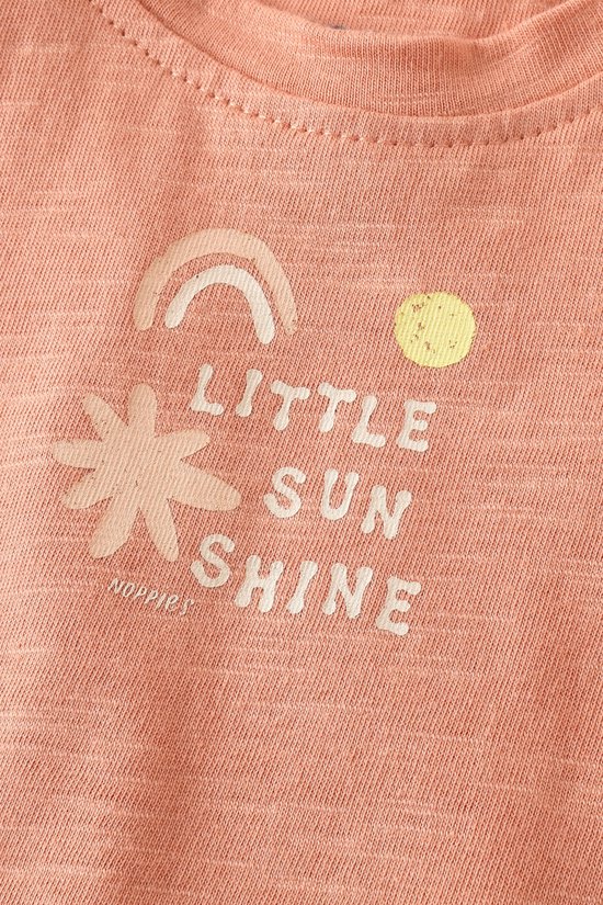 Oranje t-shirt met korte mouwen en de tekst "LITTLE SUN SHINE" in witte letters, met een regenboog en zon-illustratie.