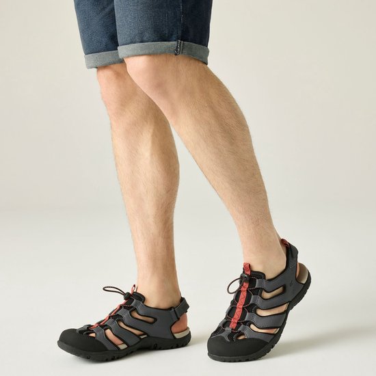 Model met Regatta sandalen aan, grijs met oranje, en een denim short.