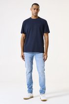 Man met donkere huid in een donkerblauw T-shirt en lichtblauwe spijkerbroek.