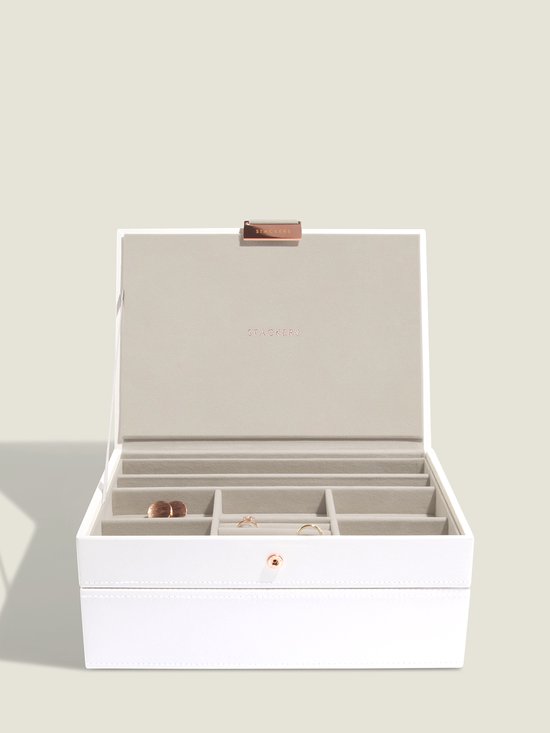Witte juwelendoos met beige voering, met gouden ringen en oorbellen.