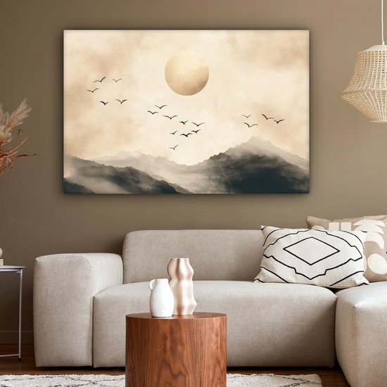 Toile paysage abstrait avec montagnes, grand cercle doré et oiseaux en vol, accrochée au-dessus d'un canapé.