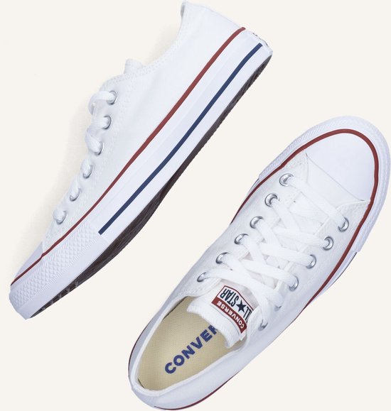 Twee witte lage Converse sneakers, een van de zijkant, een van boven.