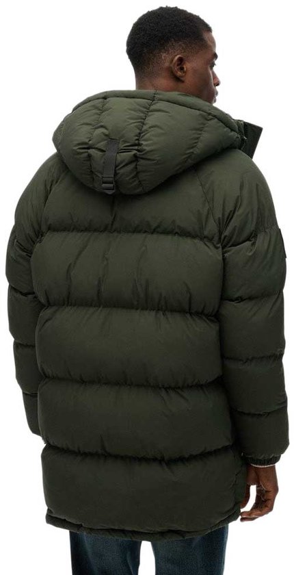 Een man, van achteren gezien, draagt een lange, donkergroene, gewatteerde parka met capuchon.