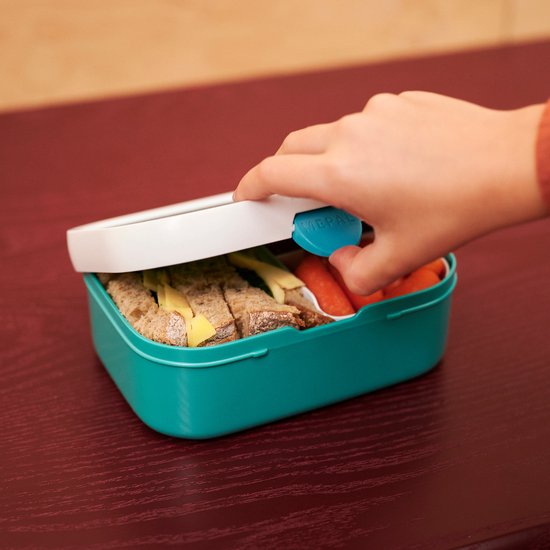 Enfant ouvrant une boîte à lunch turquoise avec des sandwichs et des carottes.