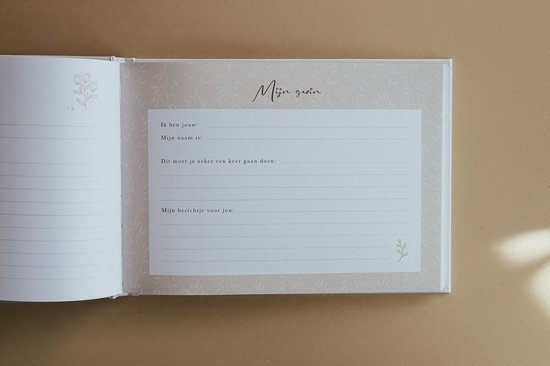 Een open kraamvisiteboek met een zachtgroene achtergrond en botanische print. De rechterpagina bevat het formulier 'Mijn gezin'.