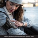 Vrouw met sporthorloge en R2B sportarmband om de linkerarm, om de telefoon te bedienen.