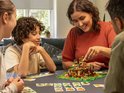 Een familie speelt LEGO Monkey Palace met een bruine, oranje en beige toren.