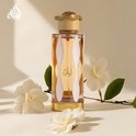 Glazen parfumfles Teriaq Lattafa met oranje vloeistof, witte accenten en een gouden slang-dop, met witte bloemen.