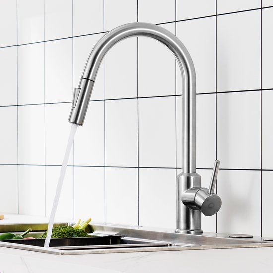 Keukenkraan van geborsteld roestvrij staal met uittrekbare slang die water sproeit in een gootsteen.