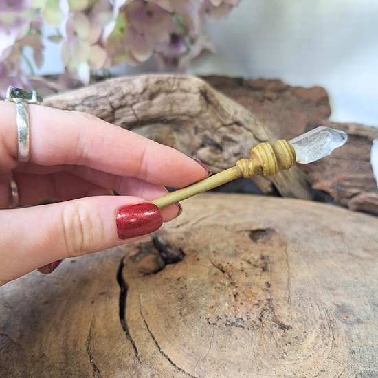 Hand met rode nagellak die een gouden toverstafje vasthoudt met bergkristalpunt.