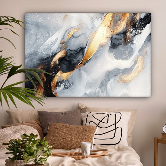 Abstract schilderij in goud, grijs en wit, hangend boven een bed met veel kussens.