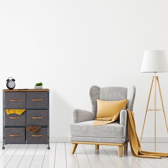 Grijze ladekast met 3 vakken, houten blad, houten handgrepen, staand naast een fauteuil.