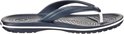 Donkerblauwe Crocs flipflop met witte strepen op de zoolrand. De bandjes zijn donkerblauw met een witte tussenruimte.