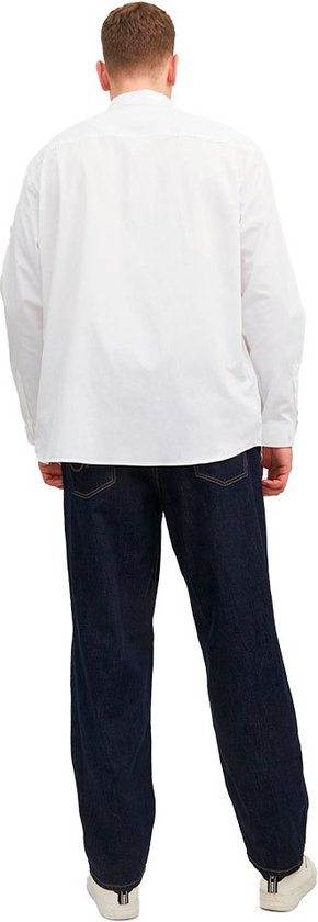 Man van achteren gezien, draagt een wit Jack & Jones overhemd en donkere jeans.