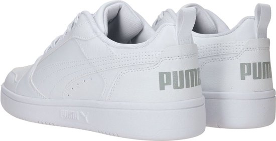 Twee witte PUMA sneakers, met grijze PUMA-letters op de hiel.